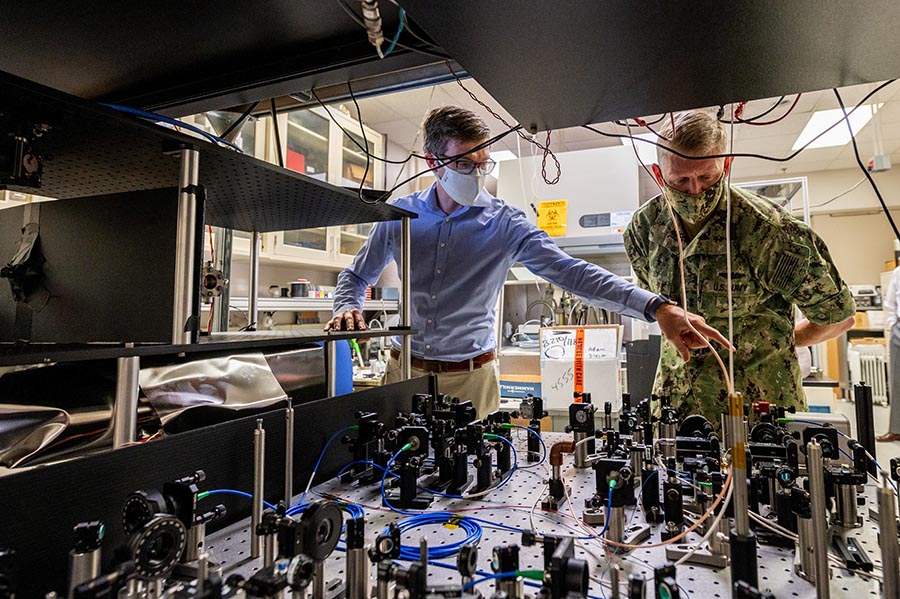 Two people look at a table filled with research equipment.