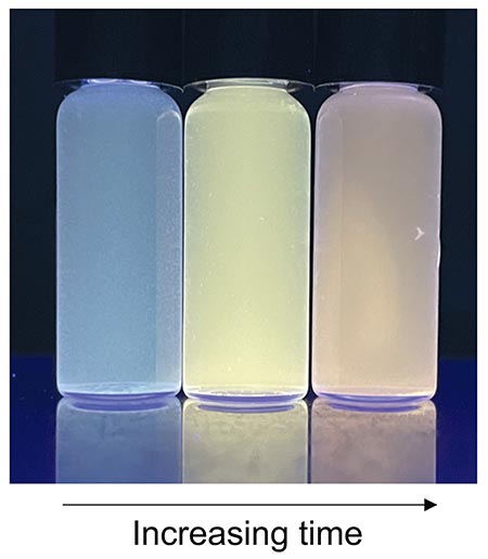 Three vials filled with blue, yellow, and orange liquid, respectively from left to right, which shows increasing growth time
