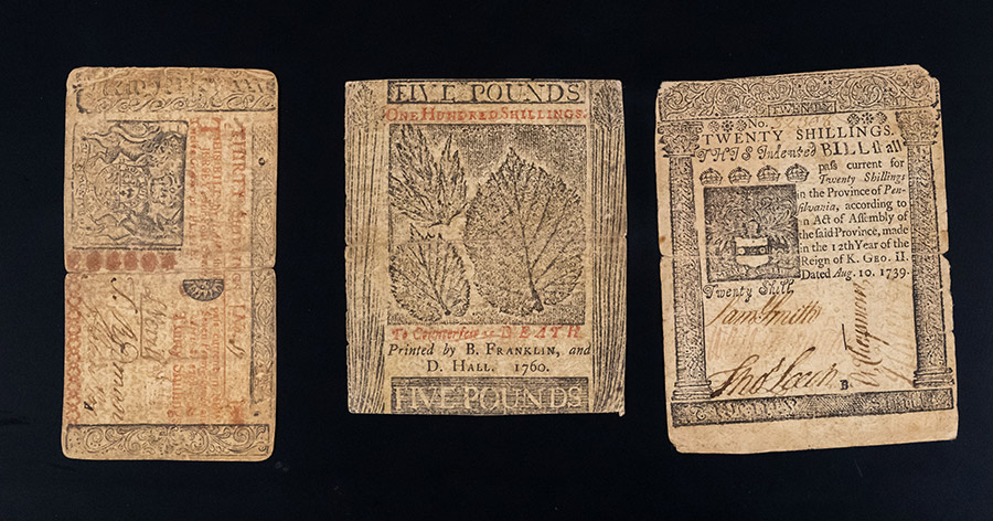 Paper bills with detailed prints of leaves, elaborately decorated columns, and thin writing. Both red and black ink is used.