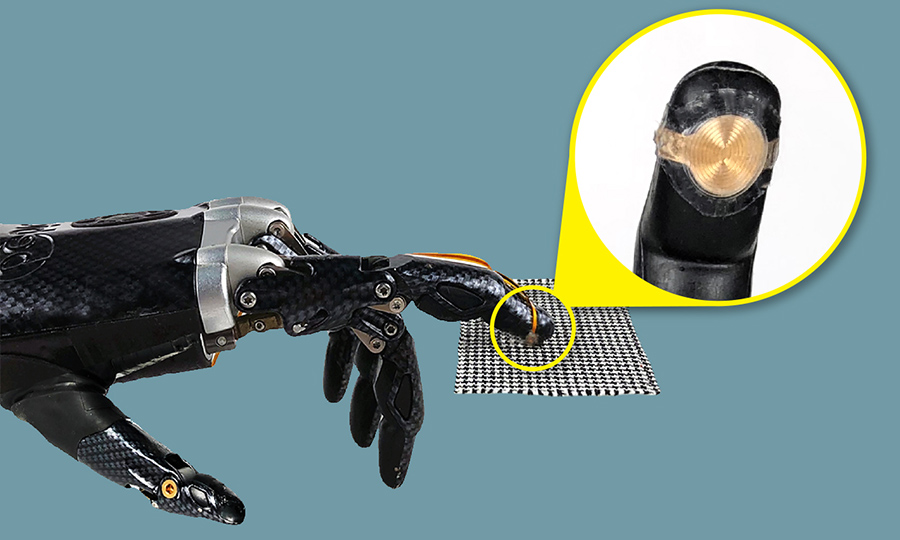 An electronic fingertip on a prosthetic hand, which is touching a piece of fabric.