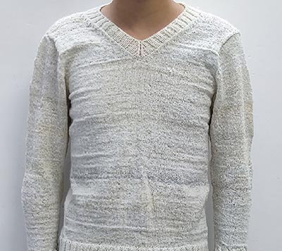 A person wearing a white, knit sweater