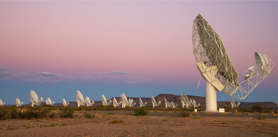 Multiple radio dishes are shown against a pastel sunset.
