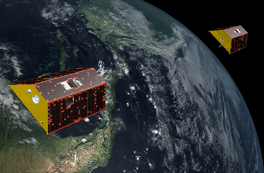 An illustration of two red, black, and yellow trapezoidal satellites hovering over the surface of Earth.