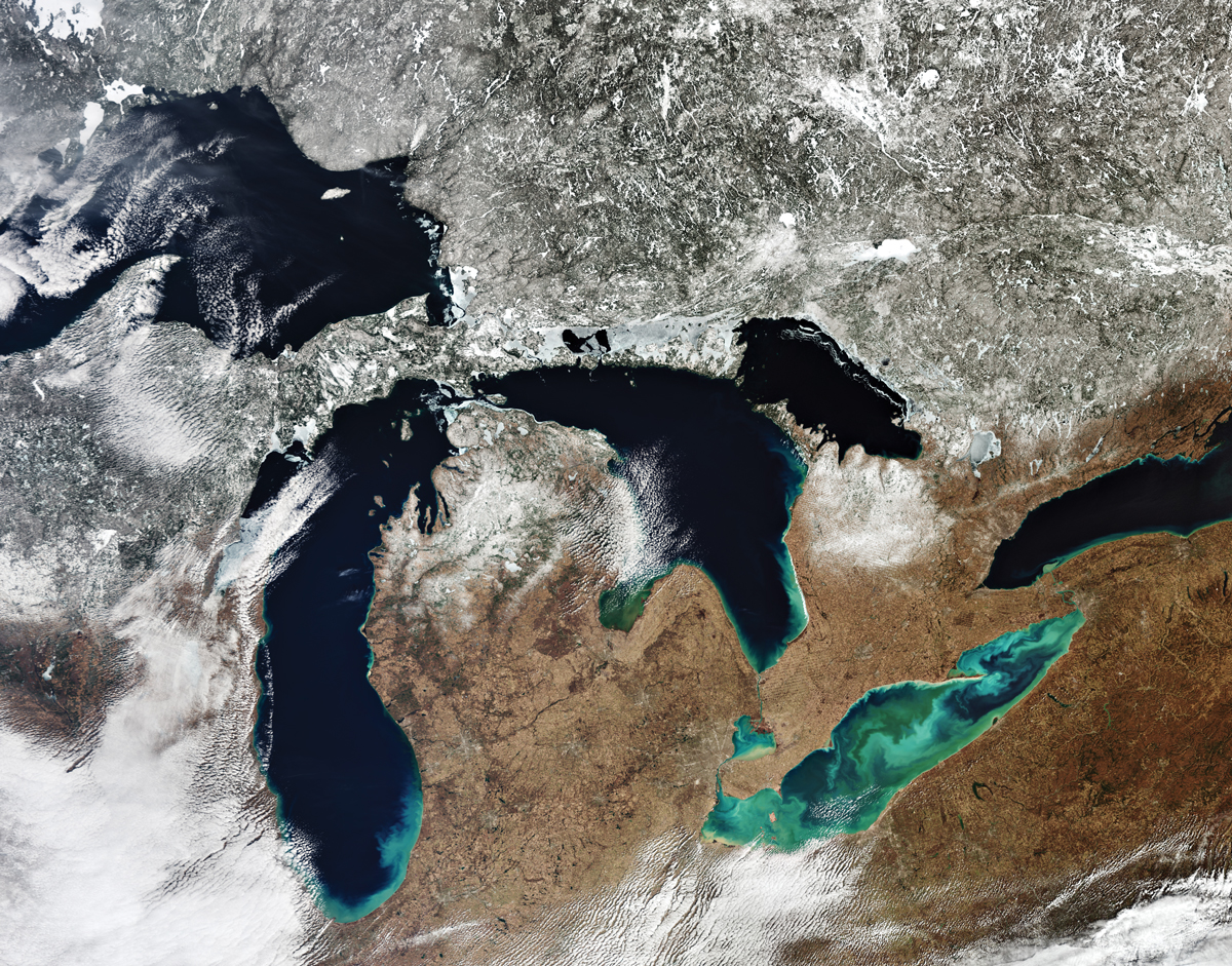 Five dark-blue to light-green lakes, as seen from space, with sparse cloud cover.