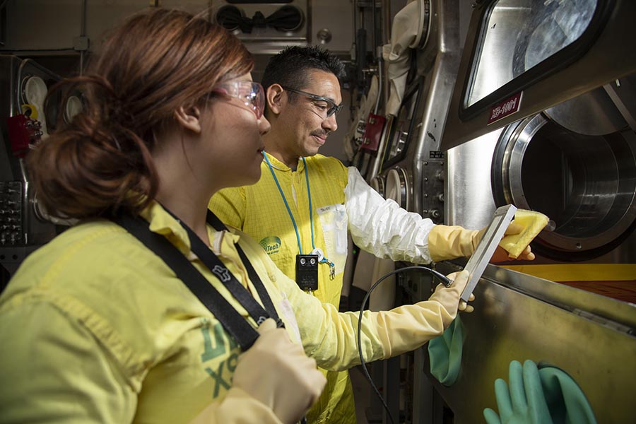 Radiological control technicians work in a glove box area