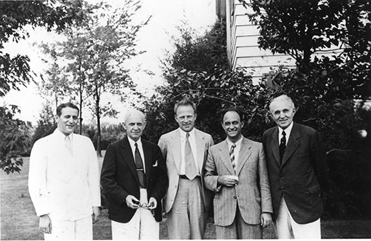 An old black-and-white photograph of five physicists grouped together