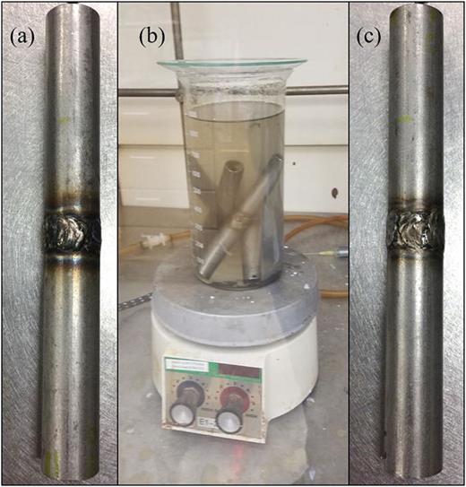 FIG. 3. (Color online) Photographs of the progression of rods from intact to damaged. (a) Undamaged 12.7 mm long, welded rod. The HAZ is evident in the discoloration. (b) Rods in the 42% solution of hot magnesium chloride (MgCl2). (c) Damaged rod after 14 days exposure in the solution. The MgCl2 bath removes much of the HAZ discoloration.