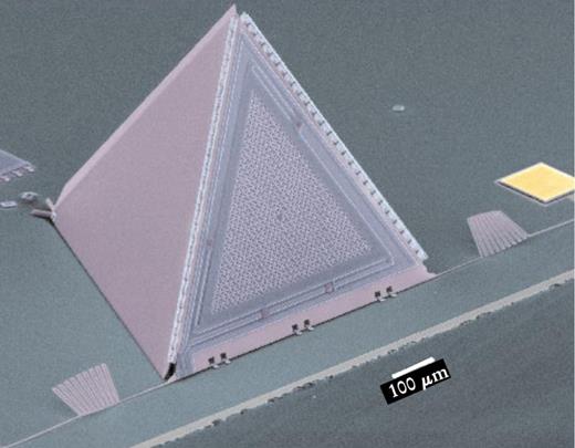  . Figure 2. A MEMS microphone is made by patterning plates in a plane and then folding them up by hand. The hinges on the edges are visible. Behind the open grill on the front is a membrane; it and the grill together form a capacitor. Sound moves the membrane relative to the grill and electronics (not shown) detect the changes in capacitance. 