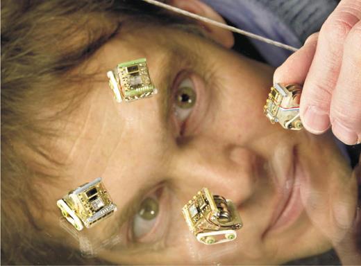  Researcher Doug Adkins inspects a group of tiny robots he and colleague Ed Heller are developing at Sandia. The robots are intelligent and communicate with each other.