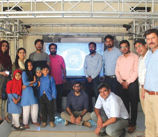 . The author (squatting), science communicators, and children from the village of Bua in the Narowal District of Pakistan pose in front of the Khwarizmi Science Society’s Large Hadron Collider Interactive Tunnel during one stop on its tour around the country. The society re-created the original LHC tunnel in collaboration with CERN’s Media Lab in 2019.