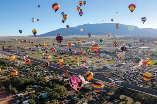 Hot-air balloons fill the sky of Albuquerque, New Mexico, throughout the year. But in the fall, the especially stable atmospheric conditions promote the Albuquerque box effect, a wind pattern that helps pilots more easily travel around. This 2023 photo is from the Albuquerque International Balloon Fiesta, which attracts thousands of tourists. (Image courtesy of Bennie Bos, Albuquerque International Balloon Fiesta.)